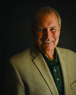 Dr. Rick Wallace Dr. Wallace headshot wearing tweed blazer with dark shirt on dark background